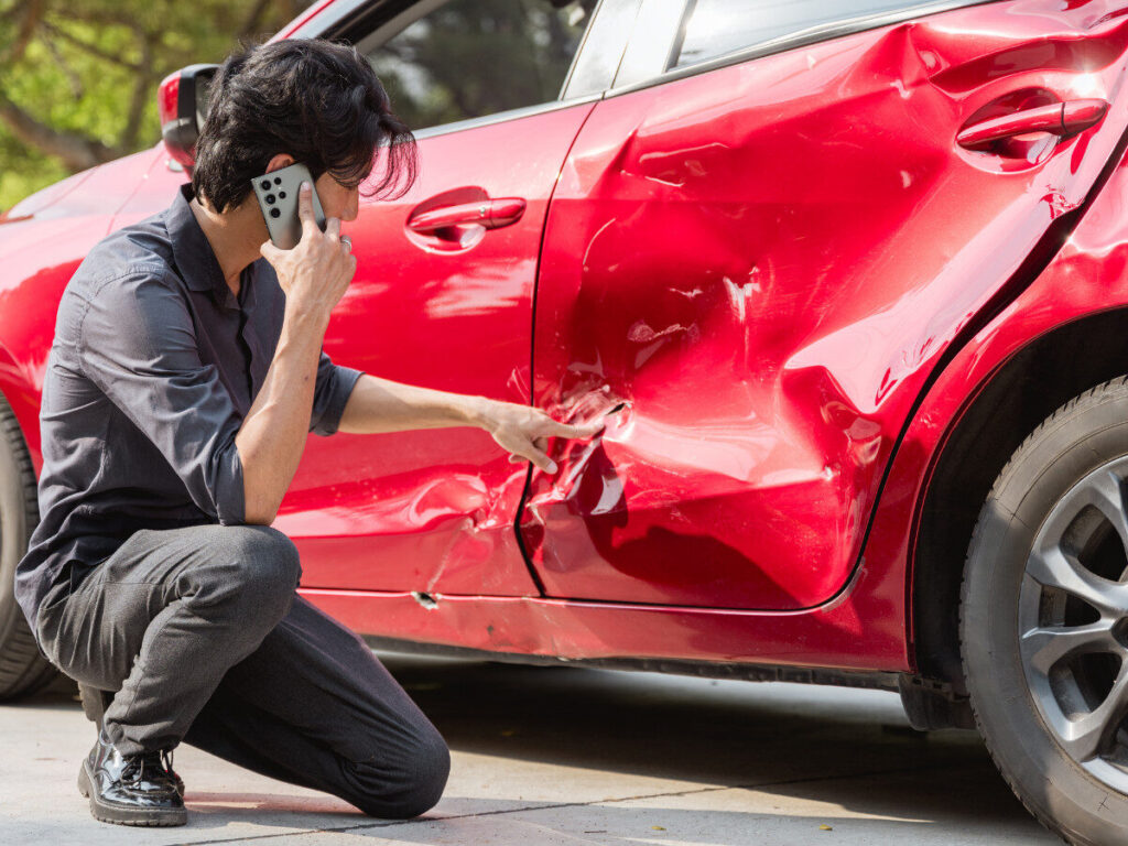 A body repair mechanic looking at the car that needs collision repair